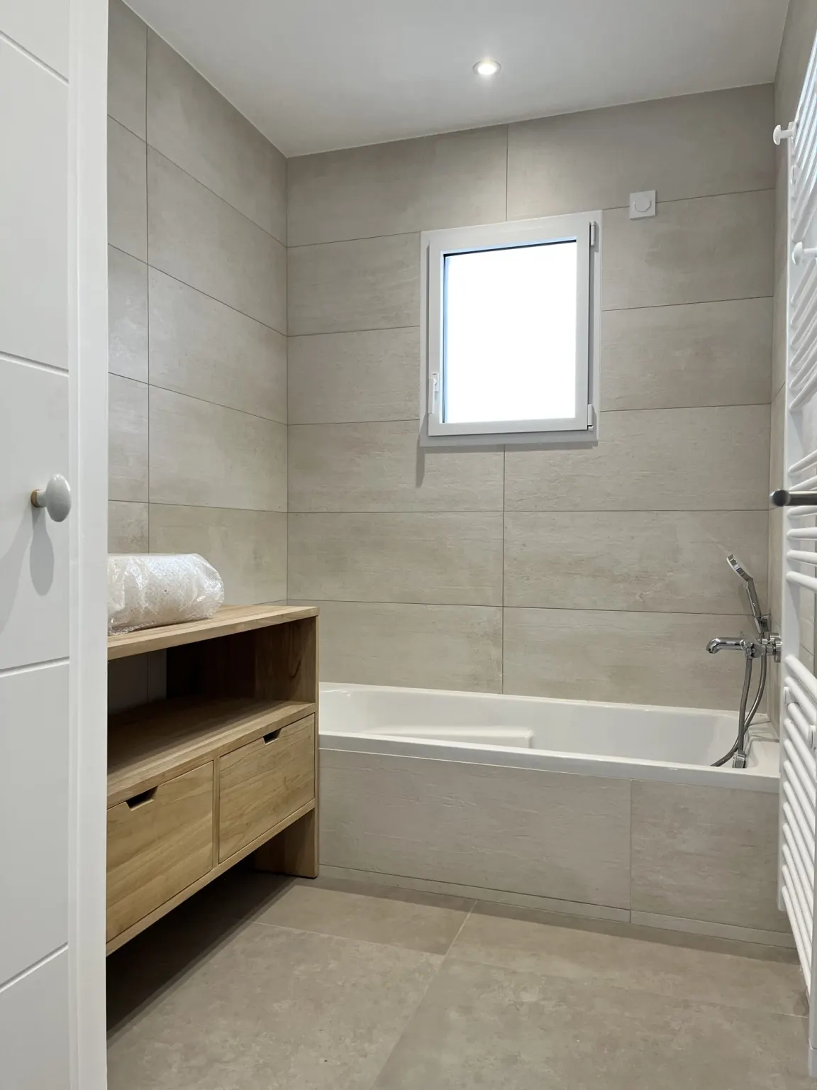 Salle de bains avec baignoire et meuble en bois — maison neuve Les Cerisiers