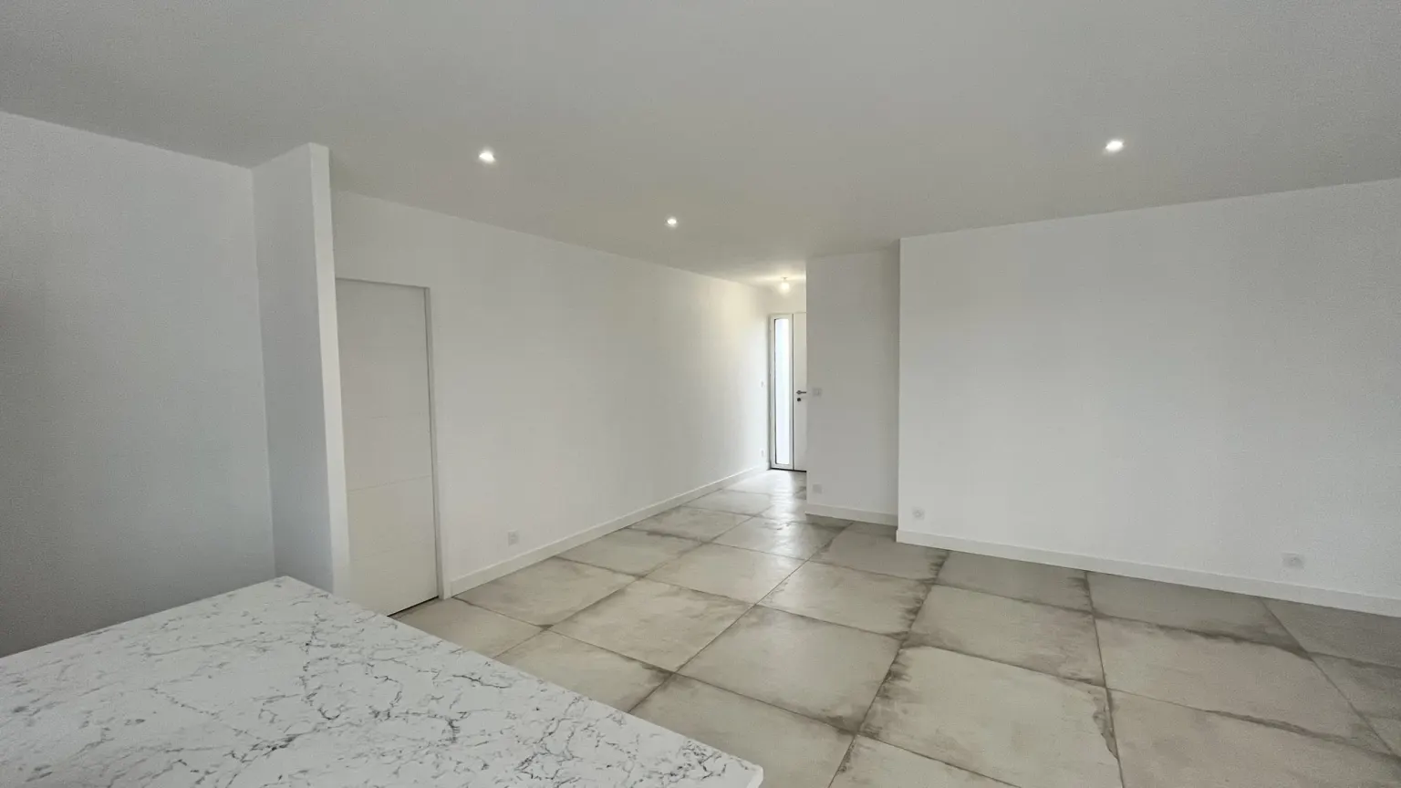 Grand séjour lumineux aux murs blancs — maison neuve Les Cerisiers