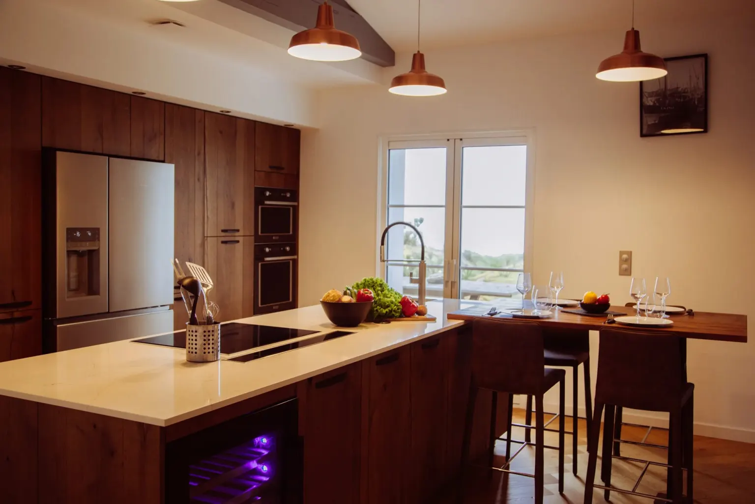 Cuisine en bois foncé avec îlot et suspensions cuivre — maison Sur la plage
