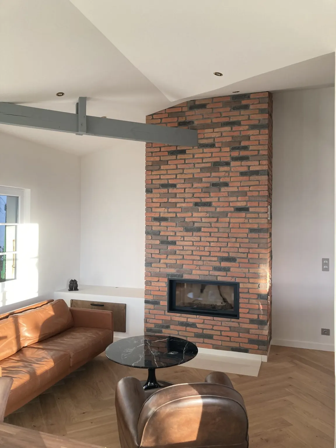 Coin salon et cheminée en briques sous charpente apparente — maison Sur la plage
