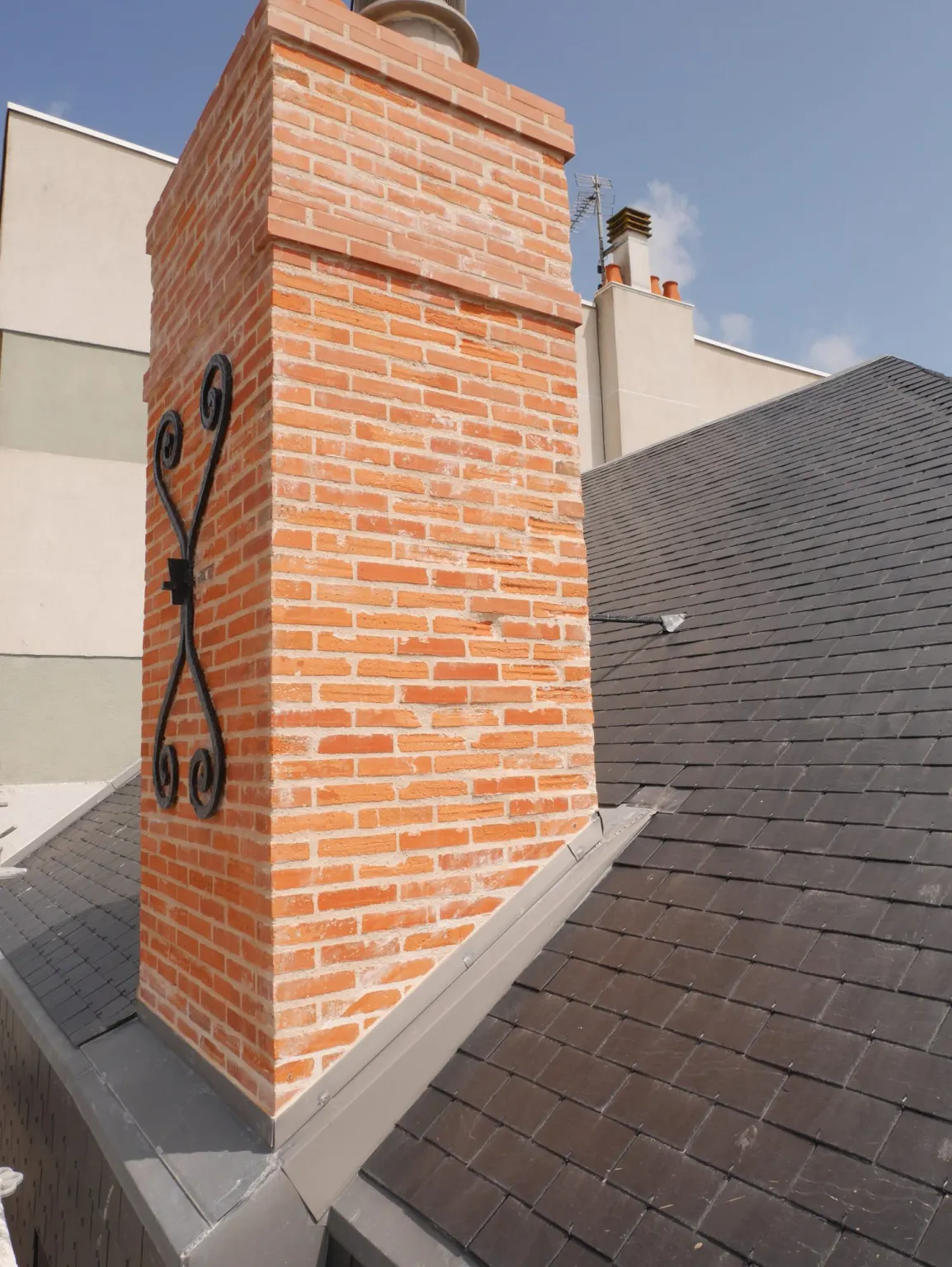 Souche de cheminée en briques refaite sur la toiture en ardoise — copropriété du Remblai