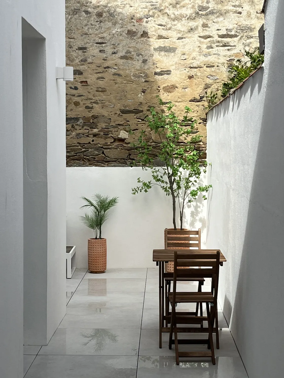 Patio blanc avec mur en pierre et coin repas — maison Le Roulis, Les Sables-d'Olonne
