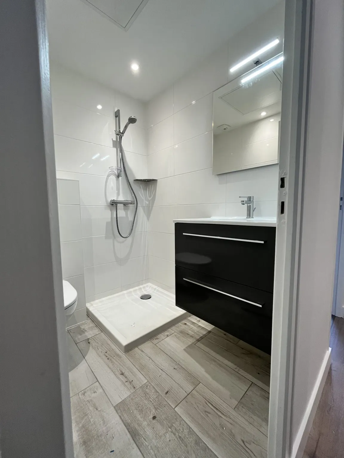Salle d'eau avec douche et meuble noir — maison Sur le Vallon